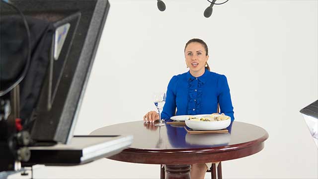 A presenter talks to autocue in a painted white infinity cove for e-learning filming