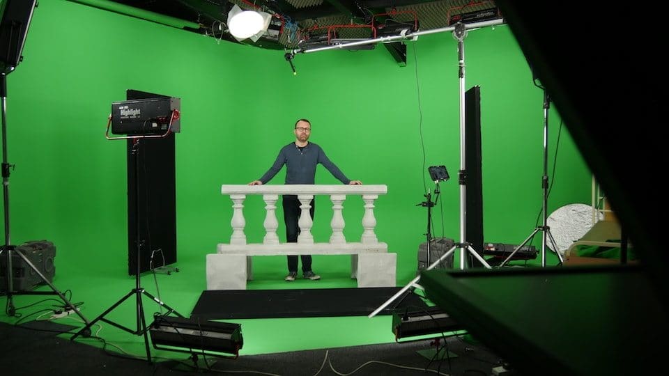 Man standing in green screen studio setup.