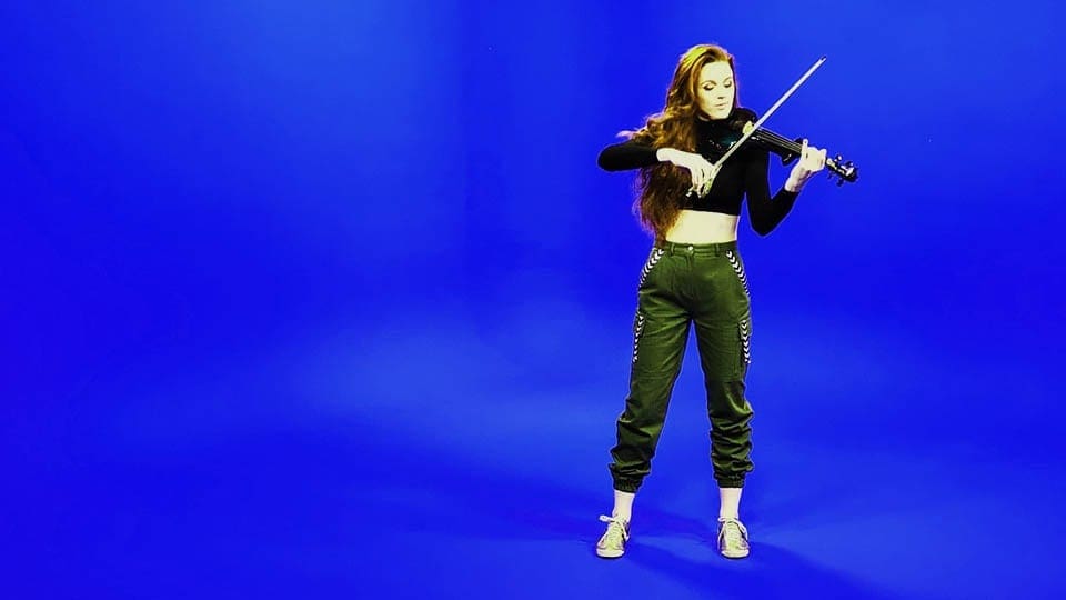 Girl plays the violin on blue screen in the Infinity Cove for a music video in Manchester