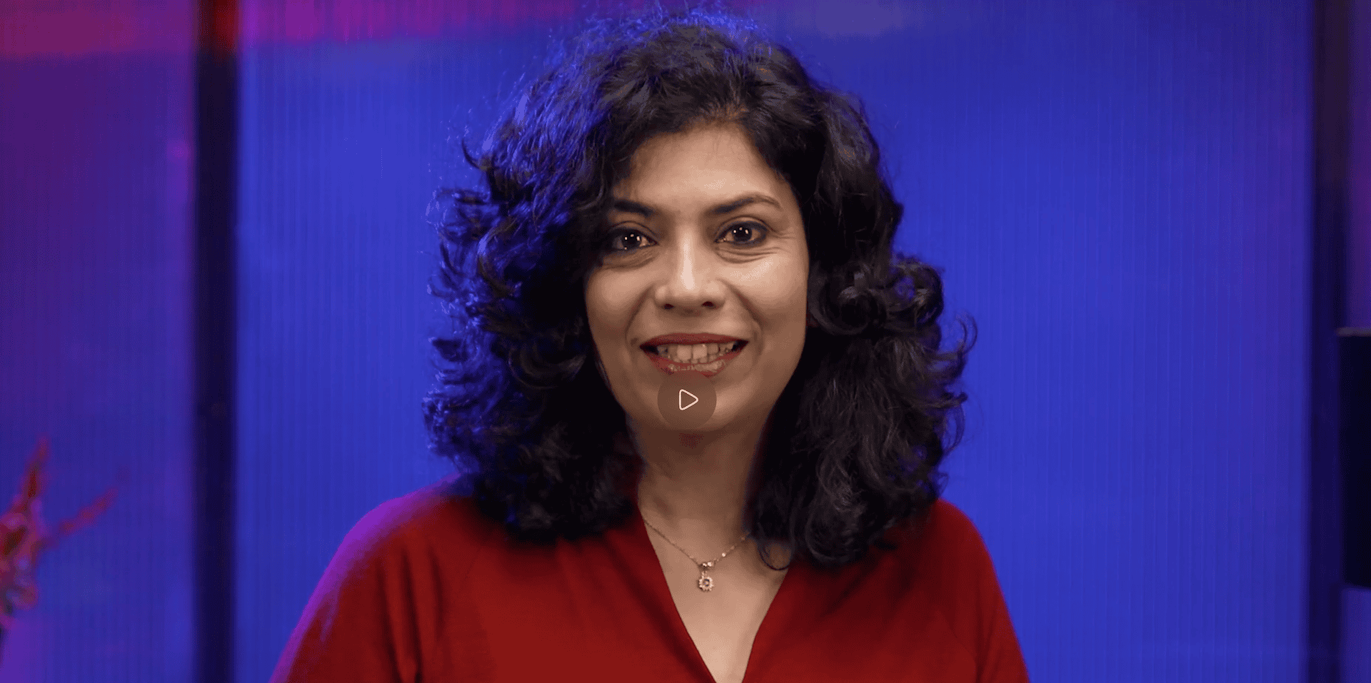 Smiling woman in red shirt against blue background