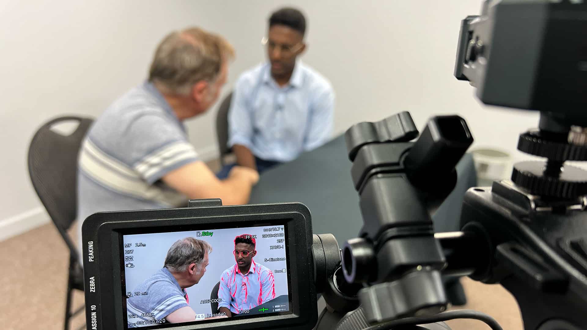 Camera capturing two people in conversation.