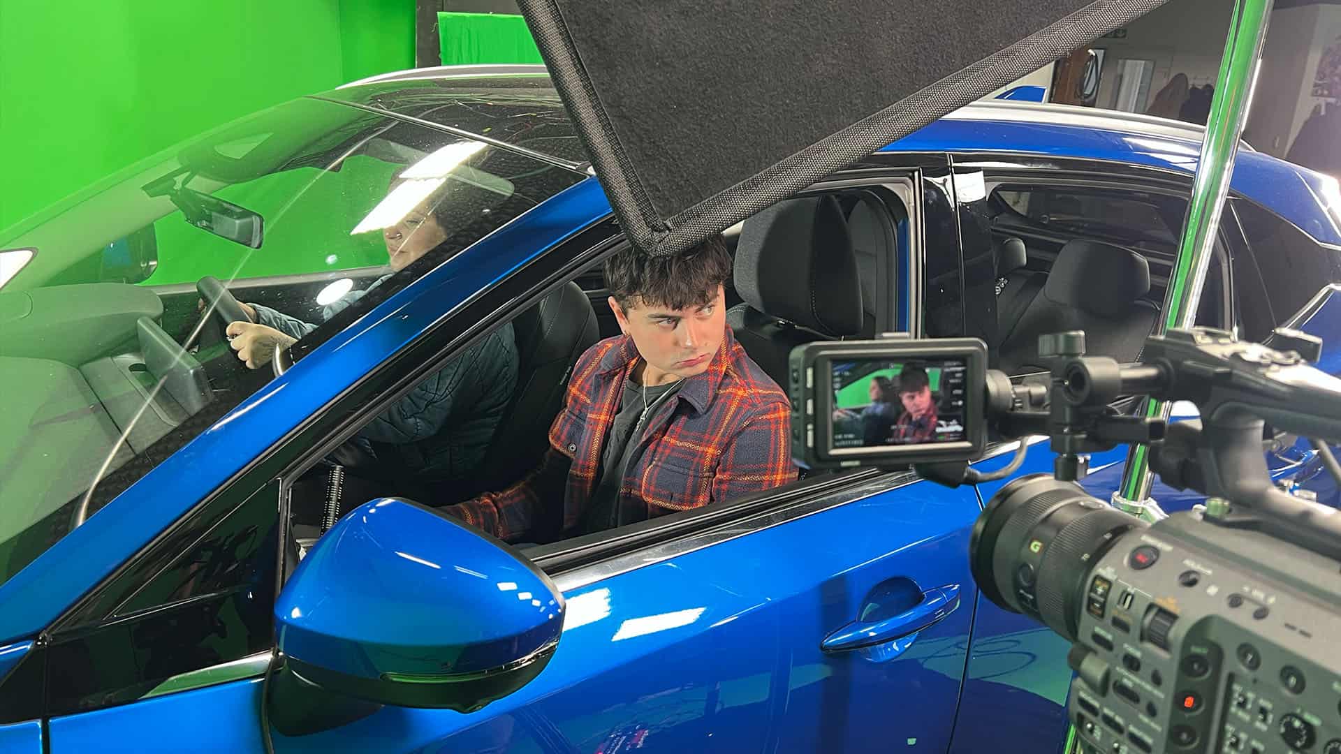 Film crew recording scene in blue car for Microdrama in greenscreen studio.