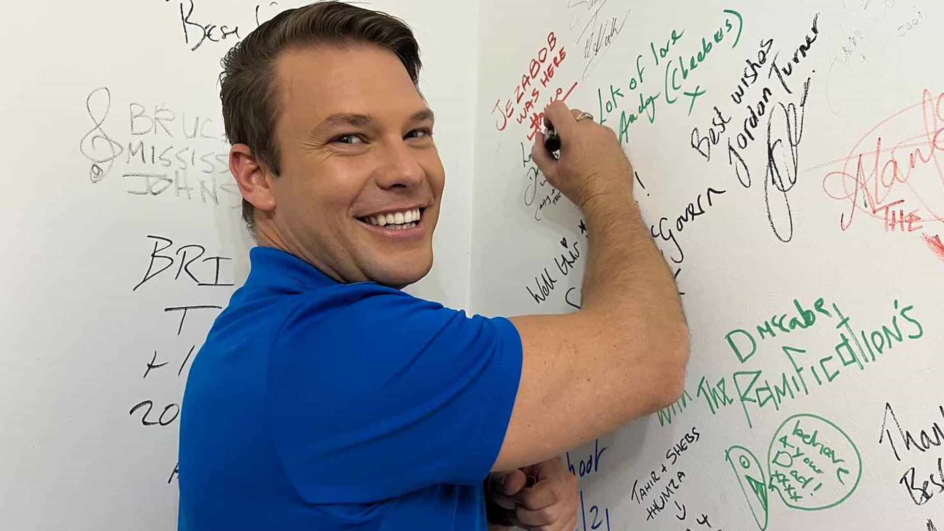 Man signing a wall with signatures.