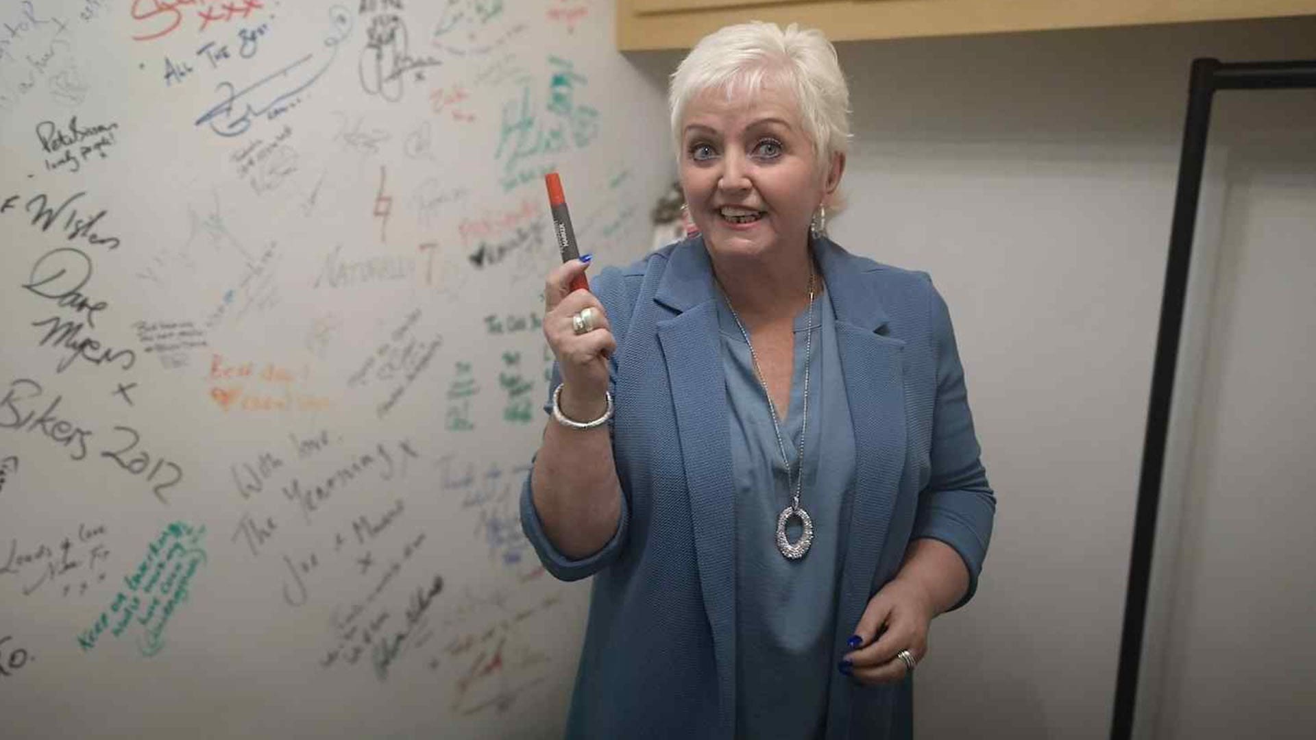 Woman holding marker standing near signed wall