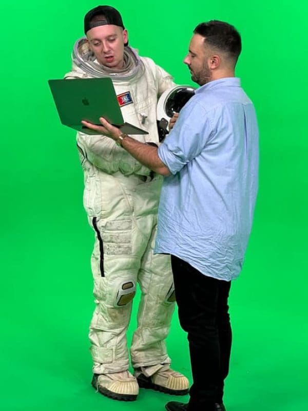 green screen backdrop - Rapper Aitch in a spacesuit takes direction from a man with laptop