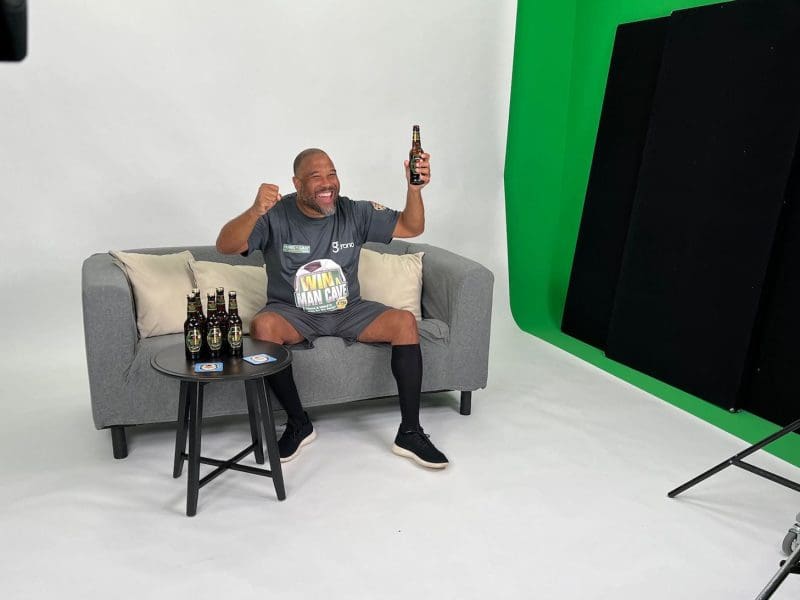 Footballer John Barnes celebrating on couch with beer bottle