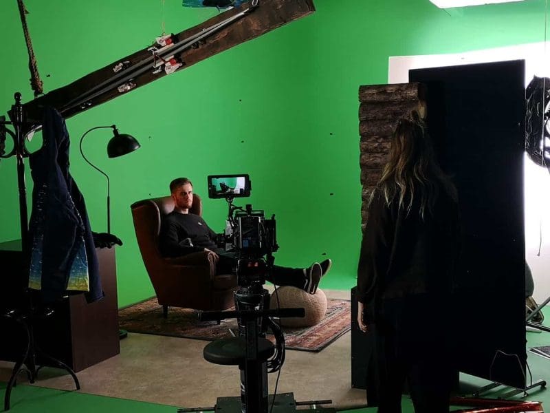 Film studio set with green screen and equipment.