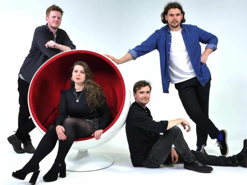 Four people posing with modern round chair in the Manchester hire studio.